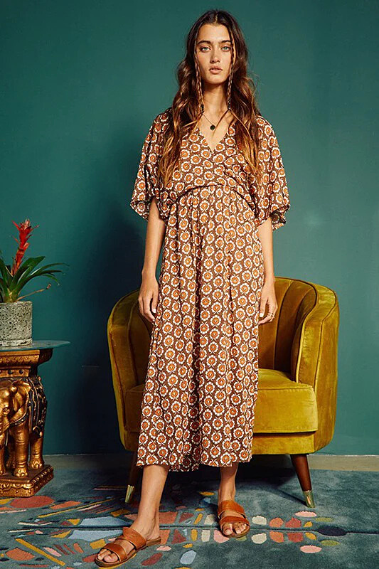 A woman wearing a kimono style midi dress in brown block print.