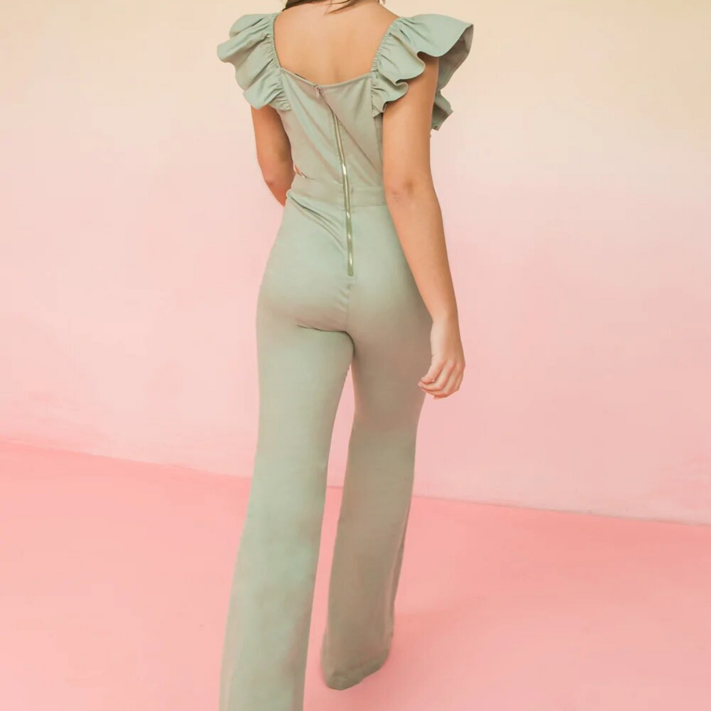 Light green jumpsuit with ruffle sleeves, flared leg, and side cutouts, worn by a woman from the back.