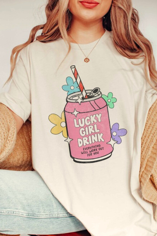 Lucky Girl Drink graphic tee with soda can, straw, sparkles and flowers with the text "everything will work out for you", worn by a woman from the front.