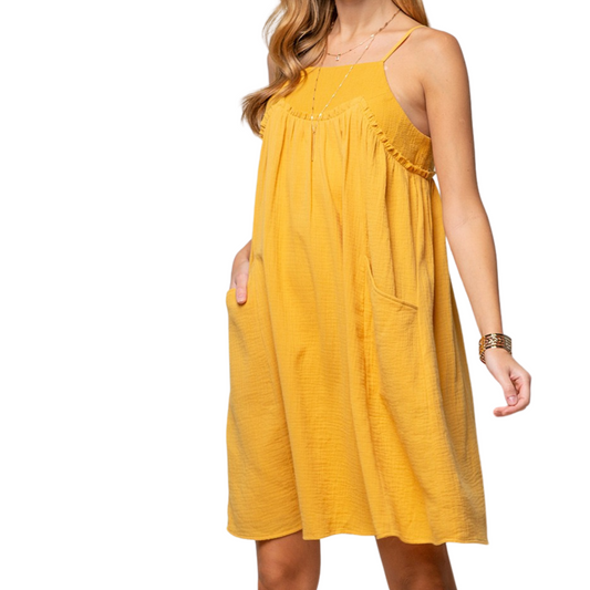 Yellow mini dress made from gauze material, with pockets and a square neckline, worn by a woman from the front.