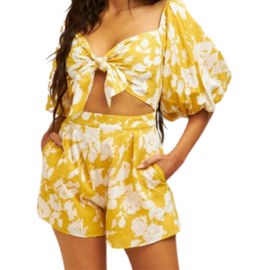 Yellow and white romper with front tie detail and balloon sleeves, worn by a woman from the front.